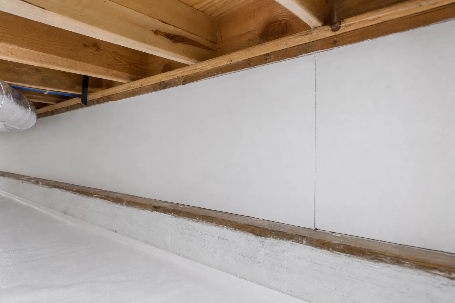 A crawl space rim joist bay sealed with rigid foam board cut clean to the bay and sealed at the edges